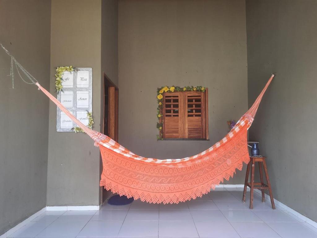 an orange hammock is hanging in a room at Linda casa com 2 quartos, um com ar e outro com ventilador, e garagem in Parnaíba