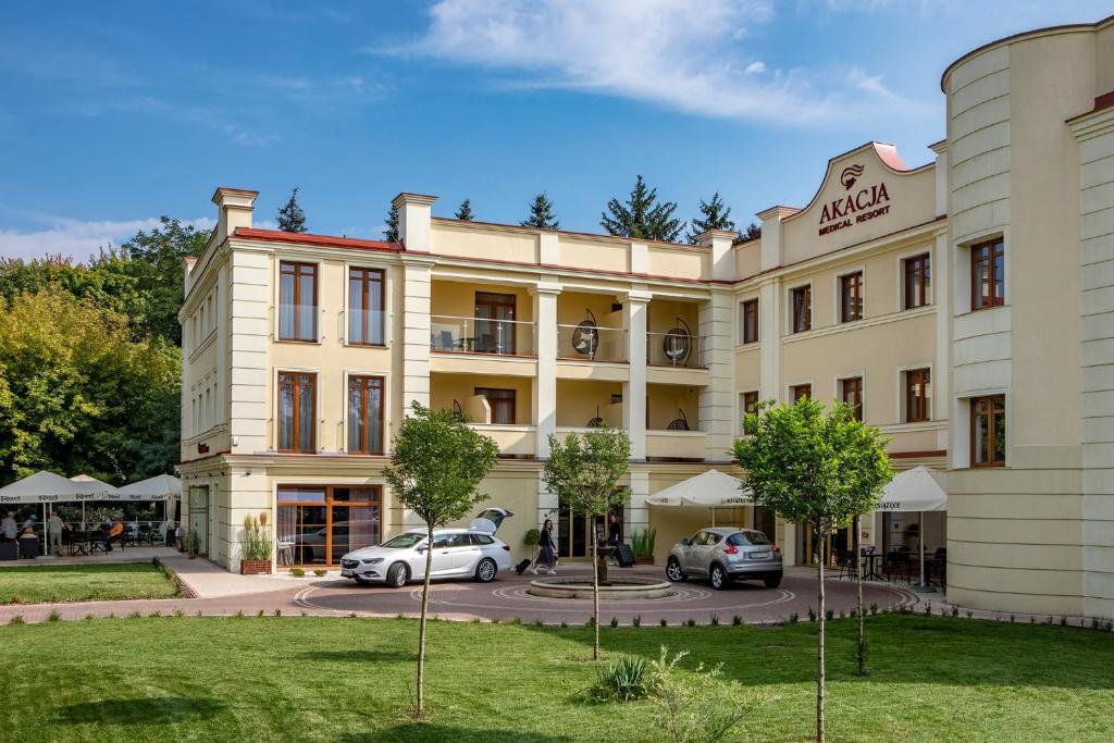 a large building with cars parked in front of it at Akacja Medical Resort in Ciechocinek