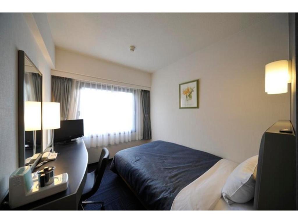 東京にあるGrand Central Hotel - Vacation STAY 19601vのベッドと机と窓のあるホテルの部屋