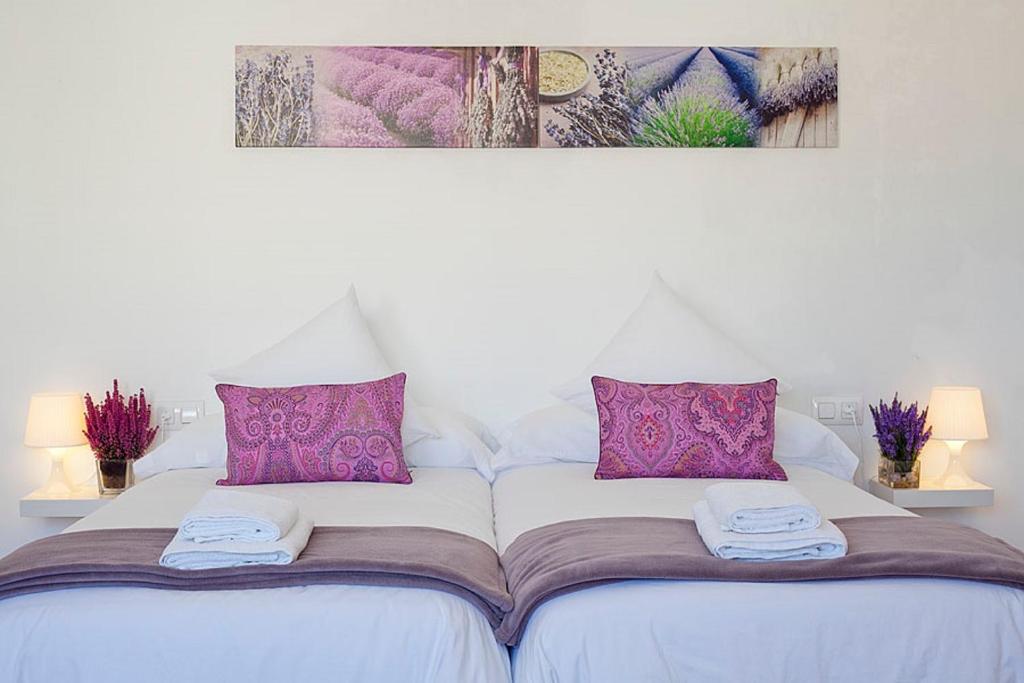 uma cama branca com almofadas roxas e toalhas em Charmsuites Paralel em Barcelona