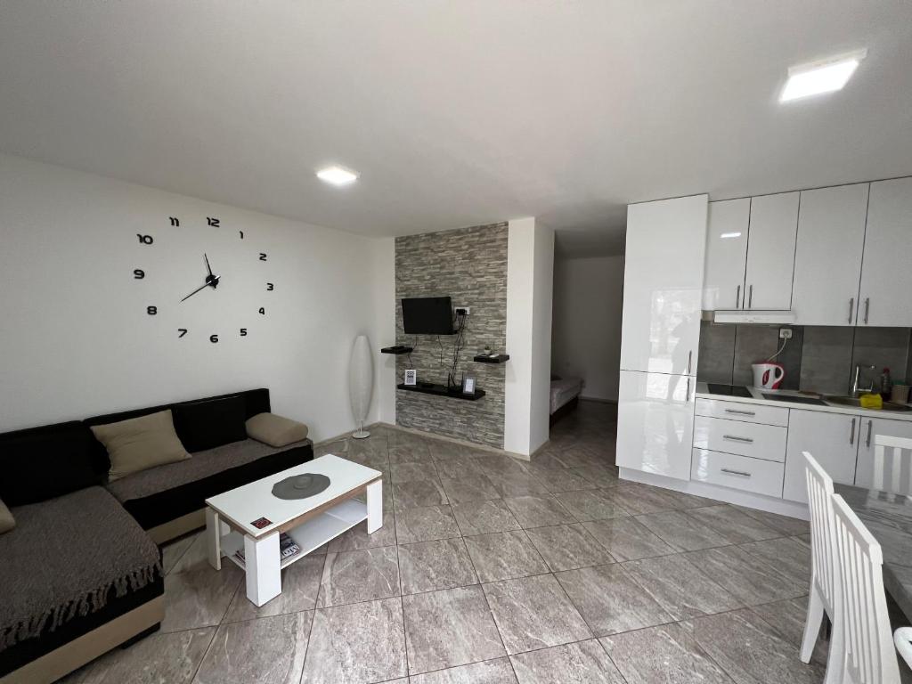 a living room with a couch and a clock on the wall at Aurora apartment in Sombor