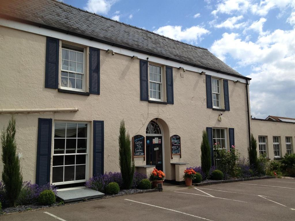 a building with blue shutters and a parking lot at Castle Lodge Wilton in Ross on Wye