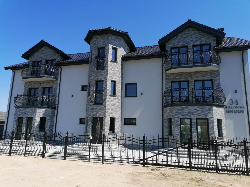 a large white building with a black fence at POKOJE GOŚCINNE AZALIOWA 34 Mielno in Mielno