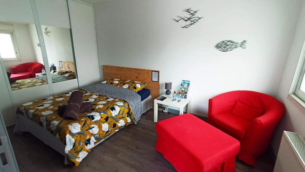 una camera con letto e sedia rossa di LauRina - Chambre, SDB, terrasse, arrivée autonome a Royan