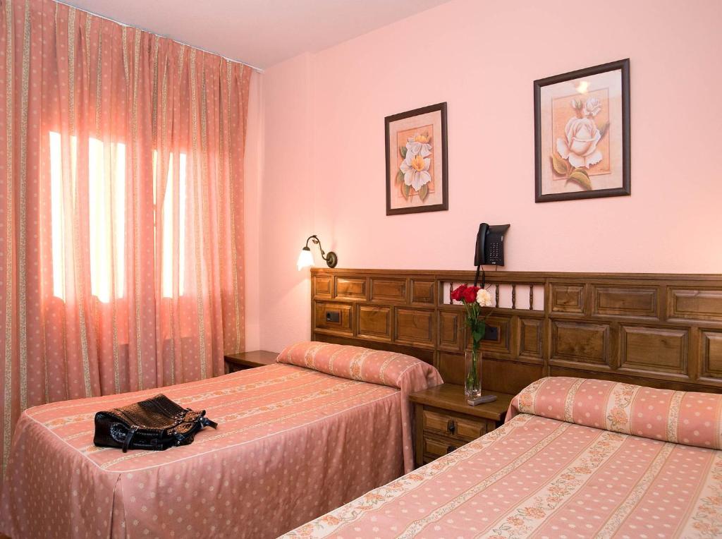 two beds in a hotel room with pink walls at Hotel Rural "Victoria" in Humanes