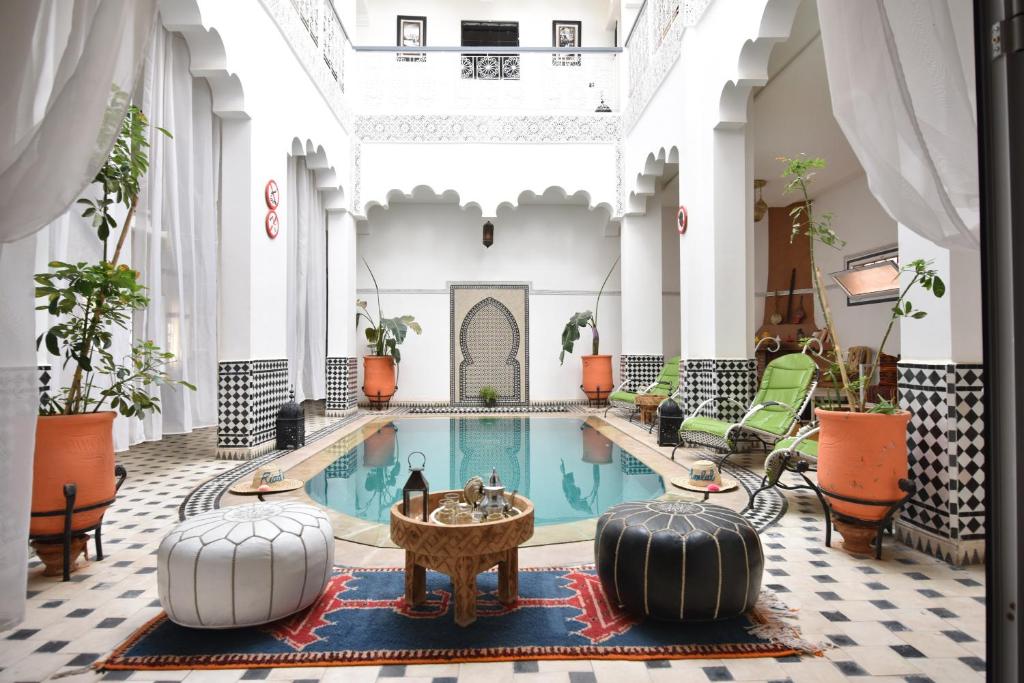 einen Hotelpool mit Stühlen und einem Tisch in der Lobby in der Unterkunft Hotel Riad Amlal in Ouarzazate