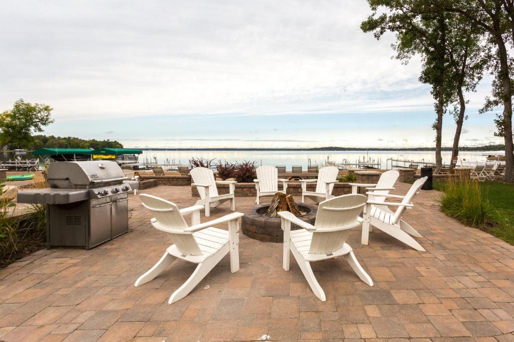 a group of white chairs and a grill on a patio at Bay Colony Unit 771 - Upper Level in Nisswa