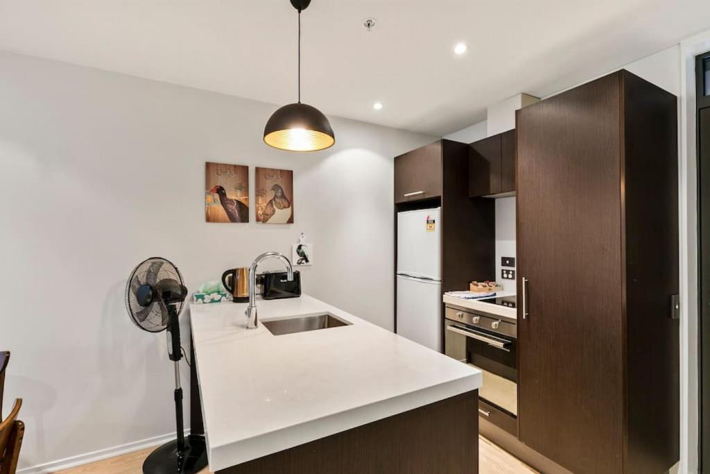 a kitchen with a white counter top and a sink at Urban City Escape with pool, gym, sauna and spa in Auckland