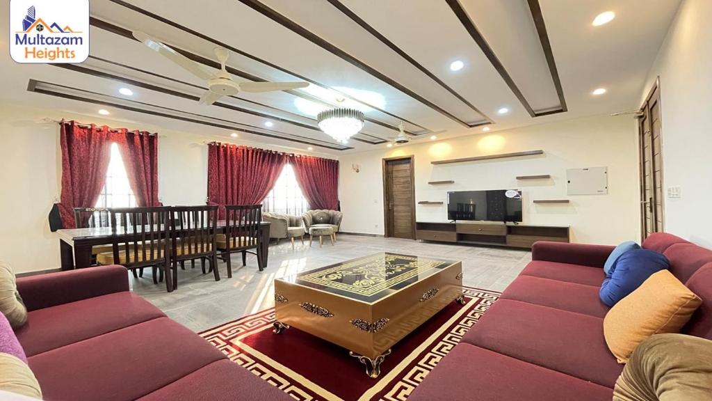 a living room with a couch and a dining room at Multazam Heights, DHA Phase 8 - Three Bedrooms Family Apartments in Lahore