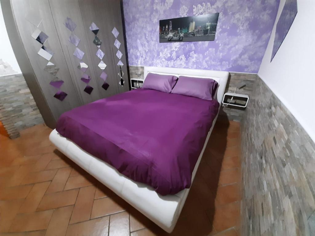 Un dormitorio con una cama morada con sábanas moradas. en Al centro del porto, en Civitavecchia