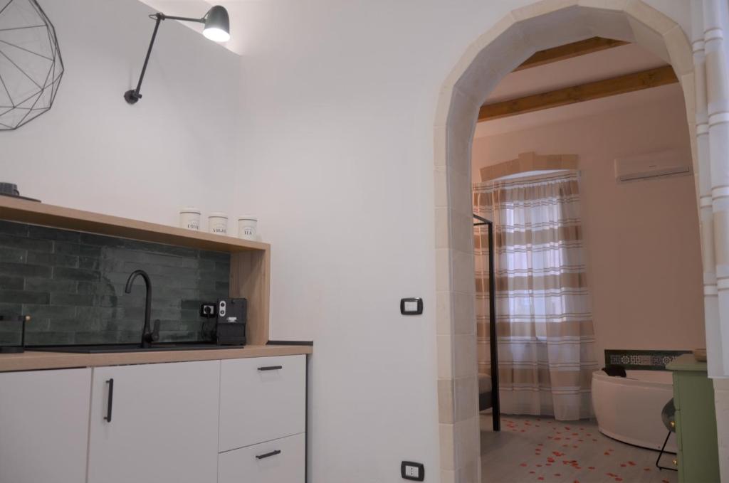 kuchnia z białymi szafkami i łukiem w obiekcie The Court Suites & Spa w mieście Tarent