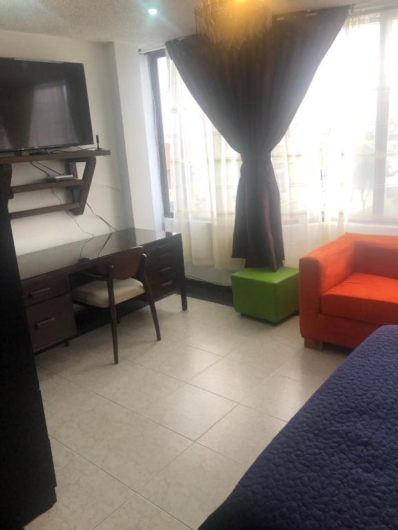 Zimmer mit einem TV, einem Sofa und einem Fenster in der Unterkunft Apt estudio calle97301 in Bogotá