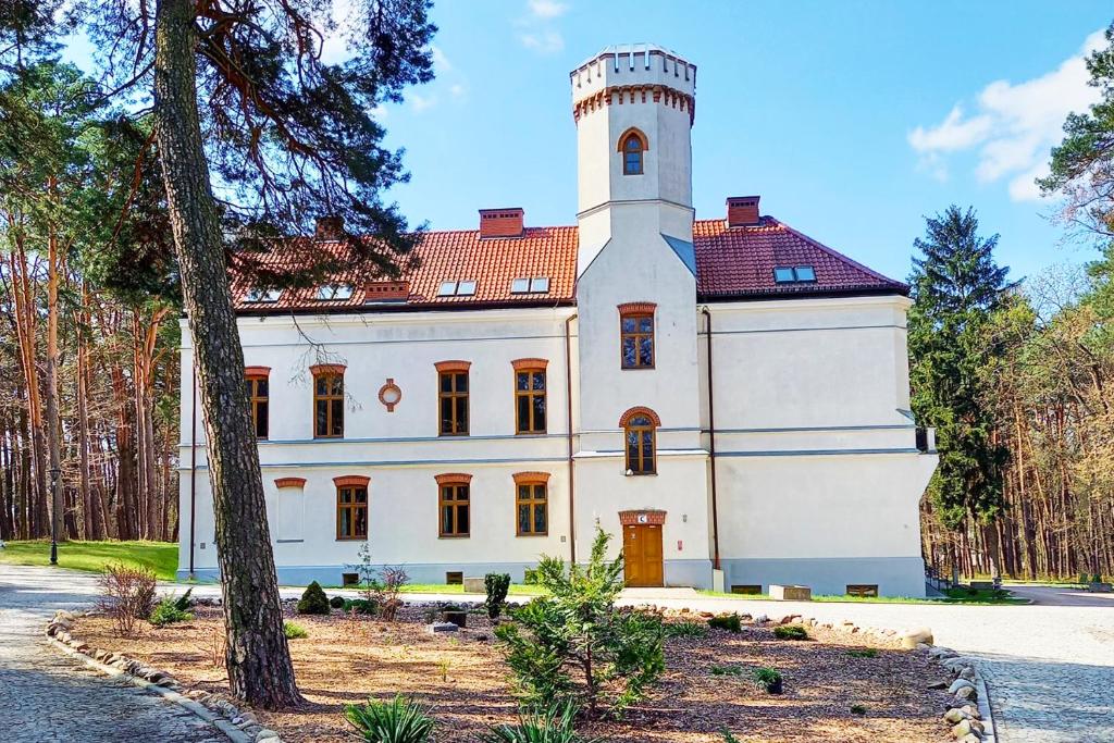 un gran edificio blanco con una torre de reloj en la parte superior en Dobry Zakątek Dom Rekolekcyjny en Konstancin-Jeziorna