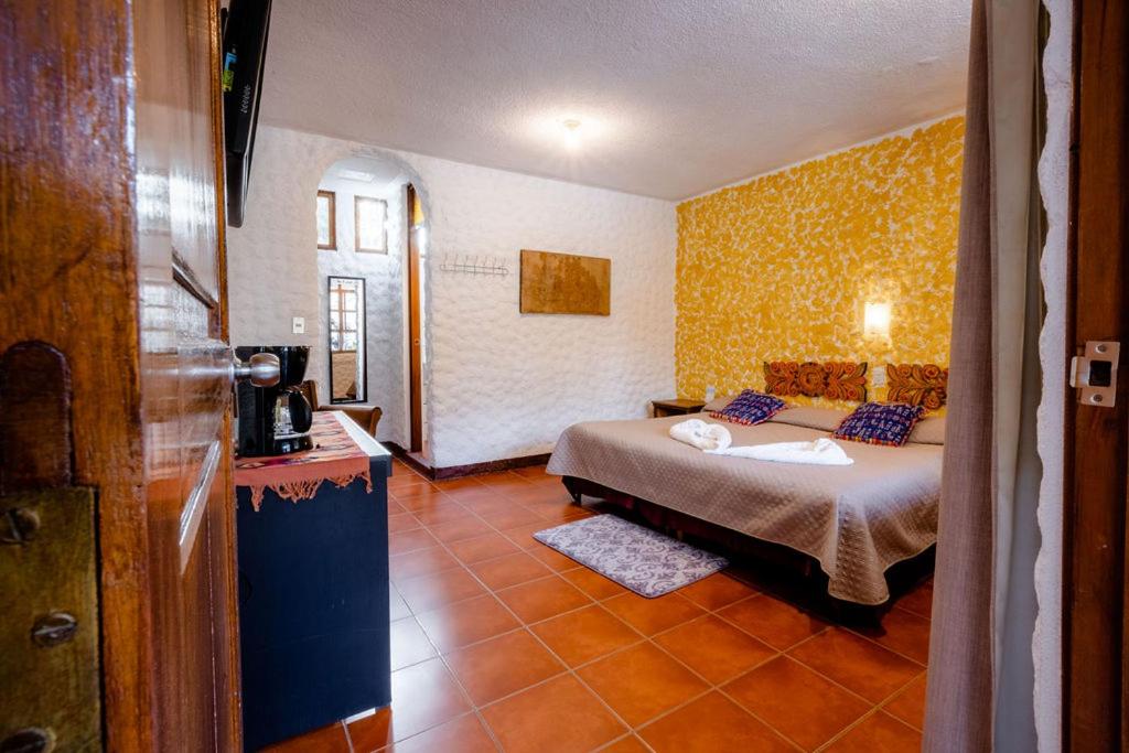 a bedroom with a bed and a yellow wall at Hotel Fonda del Sol in Panajachel