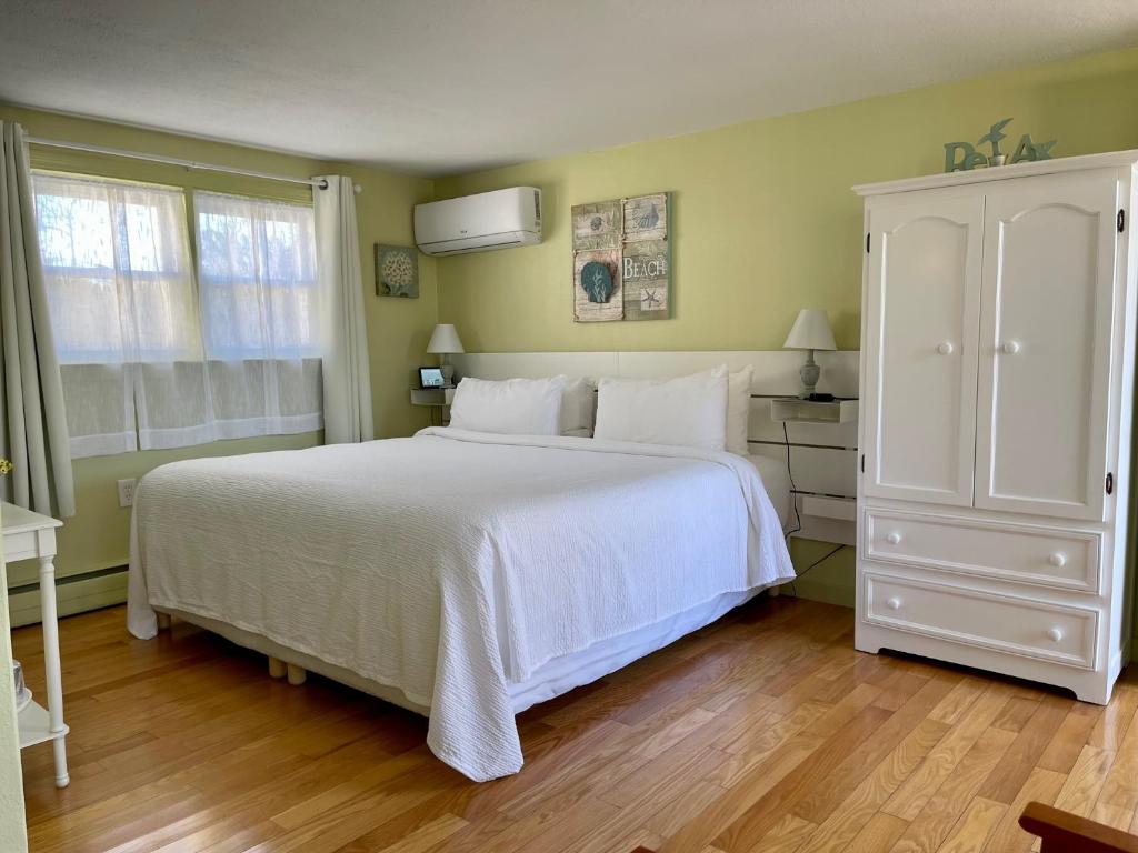 a bedroom with a white bed and a white cabinet at The Escape Inn in South Yarmouth