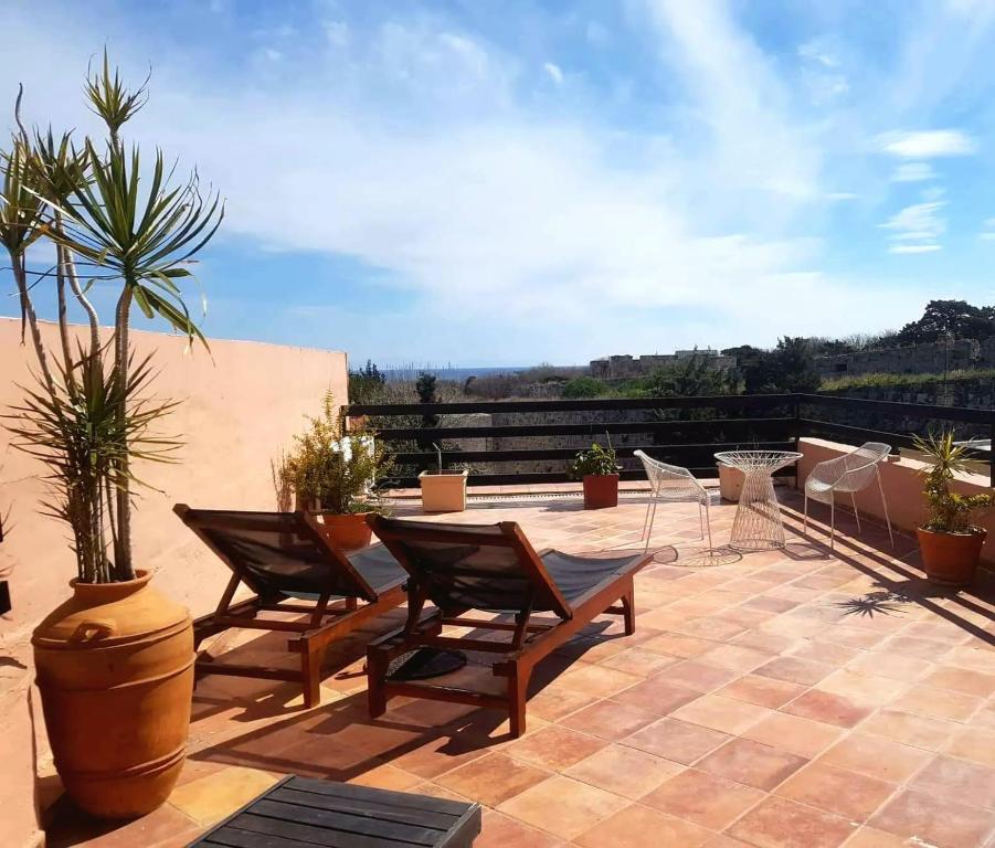 eine Terrasse mit Stühlen, einem Tisch und einer Palme in der Unterkunft Saint Michel Boutique Hotel in Rhodos (Stadt)