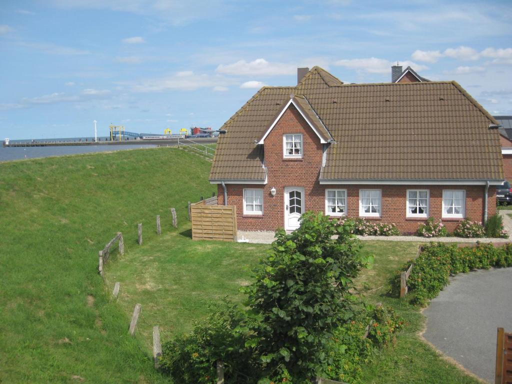 a house on the side of a field with a house at Direkt am Deich - Ferienwohnung Amrum im Gästehaus Am Badedeich in Dagebüll