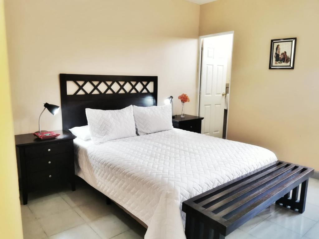 um quarto com uma cama grande e um banco ao lado em Casa Mesa em Guatemala