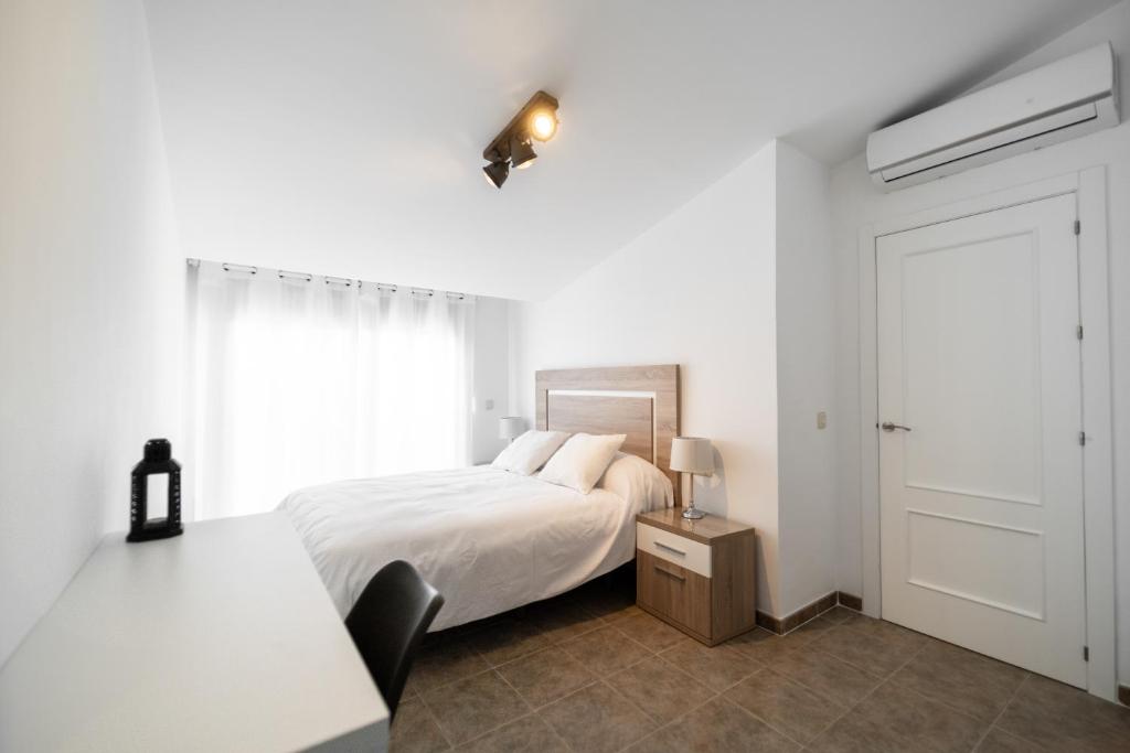 biała sypialnia z łóżkiem i oknem w obiekcie Duplex 8 Caños w mieście Ronda