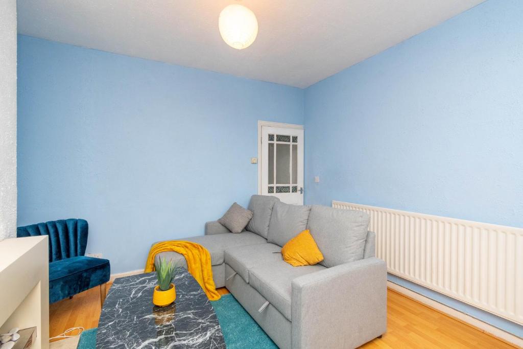 uma sala de estar com um sofá cinzento e uma parede azul em Fantastic 3 Bedroom House *Free Parking* em Wolverhampton