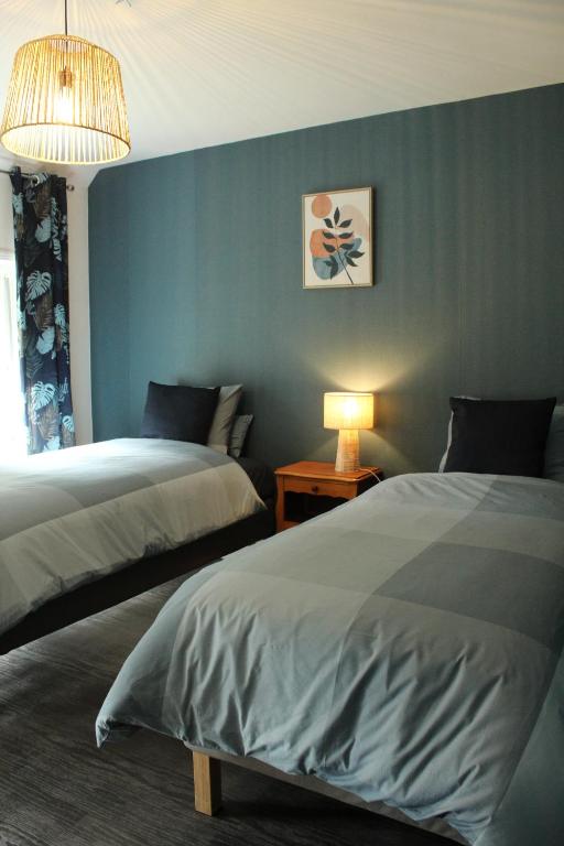 een slaapkamer met 2 bedden en een blauwe muur bij Gîte La Riviera in Wargnies-le-Grand