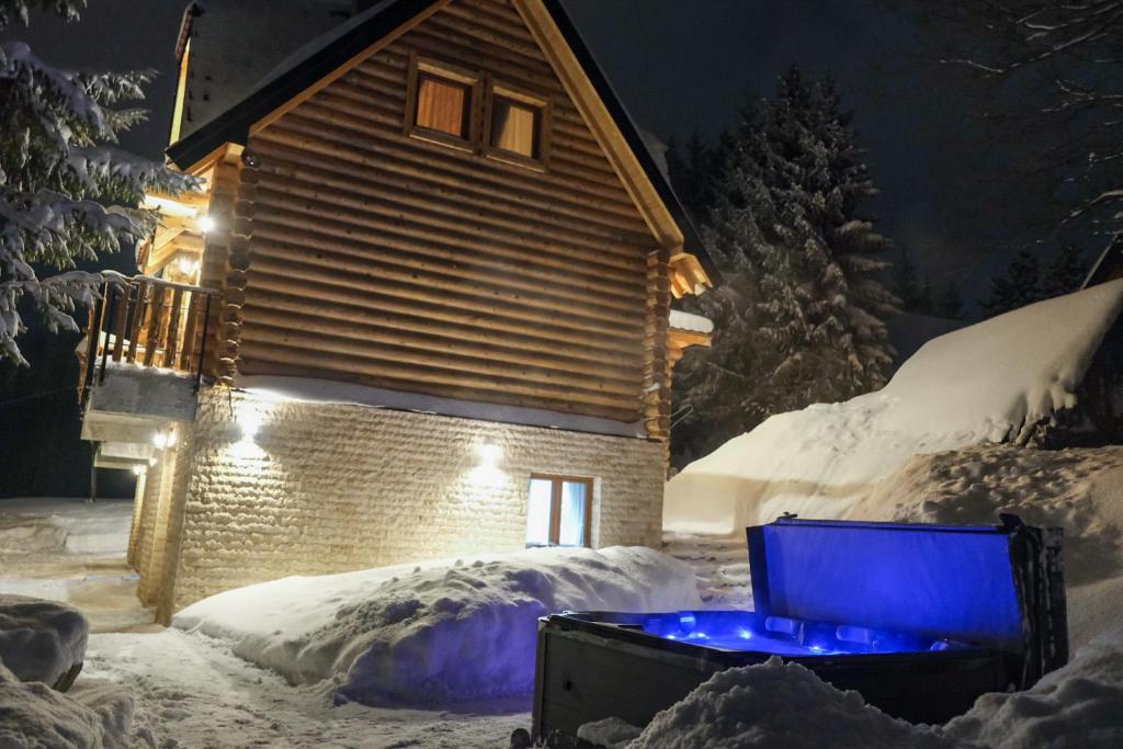 una casa con una luz azul en la nieve en Drvena Kuca RUŽA en Kopaonik