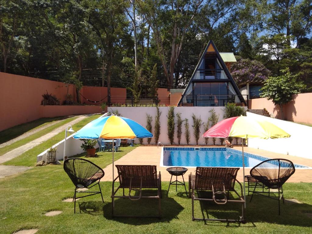 a group of chairs and umbrellas next to a pool at CHALÉ DO VALE - EXCLUSIVIDADE E CONFORTO!! in Atibaia