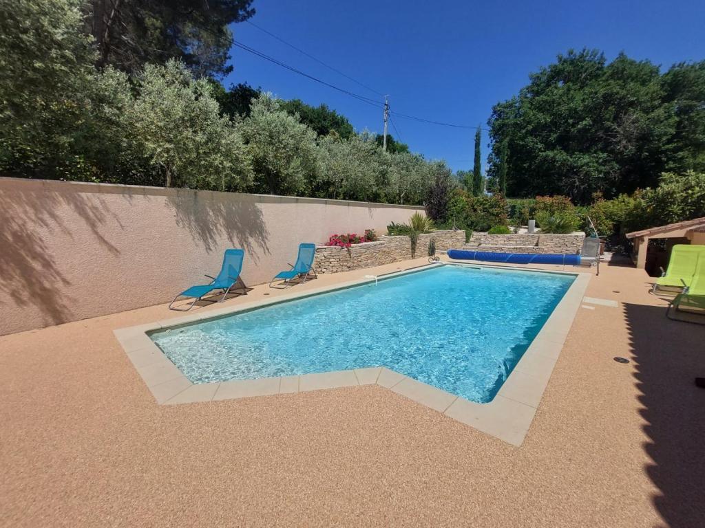 a swimming pool with two blue chairs next to it at Les girardines in Manosque