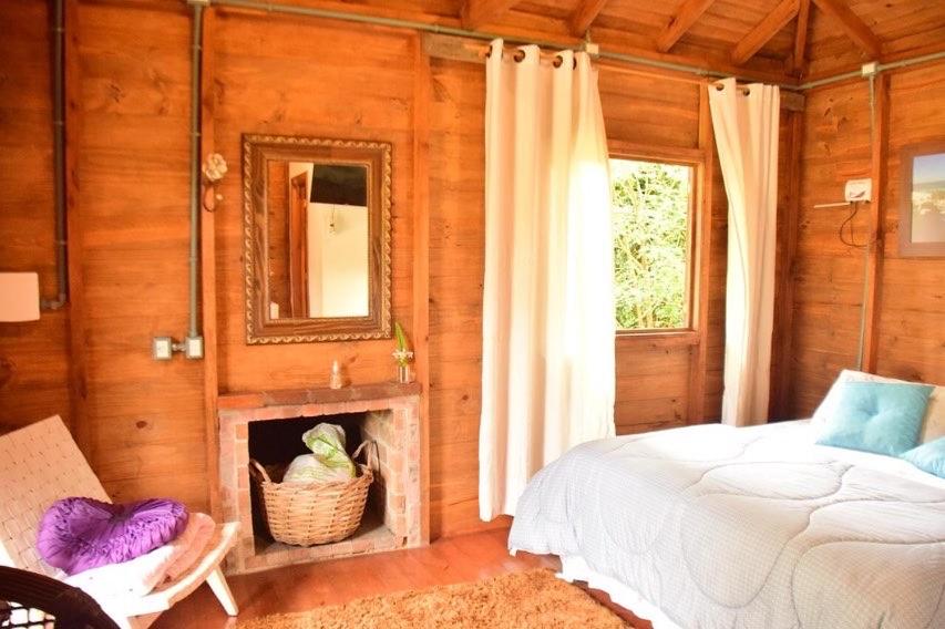 a bedroom with a bed and a fireplace and a mirror at Pousada Ananda in Osório