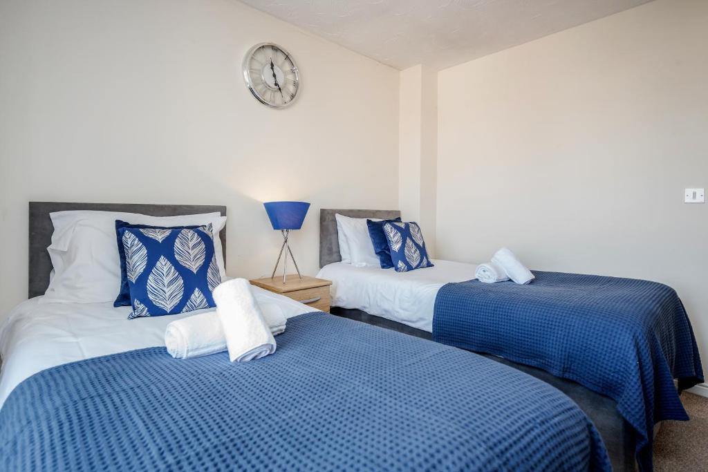 twee bedden in een kamer met een klok aan de muur bij Captivating 3-Bed Apartment in Grays in West Thurrock