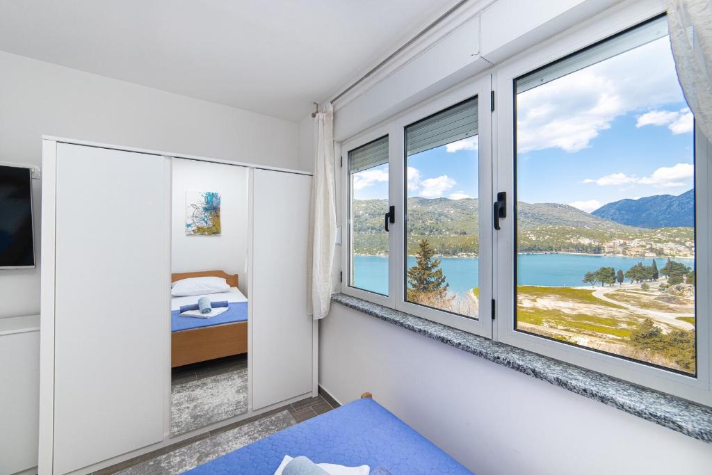 a bedroom with windows and a view of a lake at Apartment Sunrise Ploče in Ploče