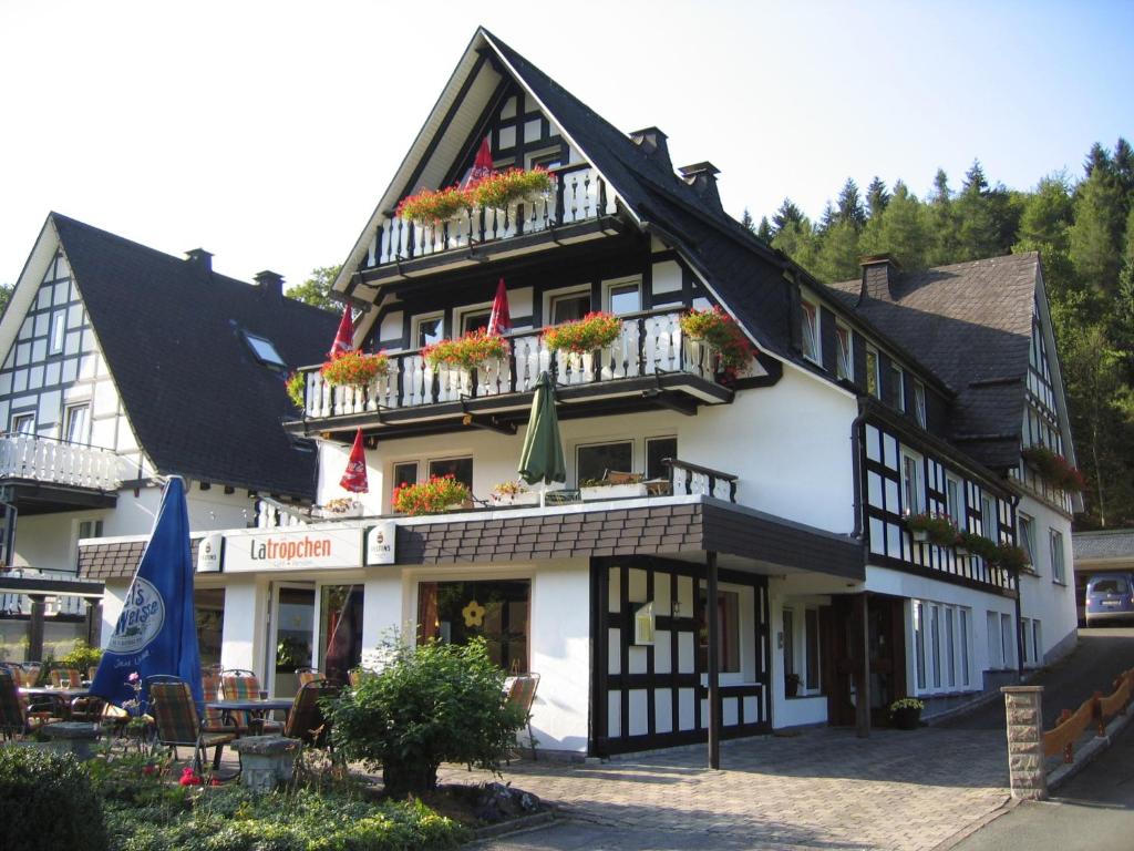 a black and white building with flowers on the balconies at Pension & Ferienhaus Latröpchen in Schmallenberg