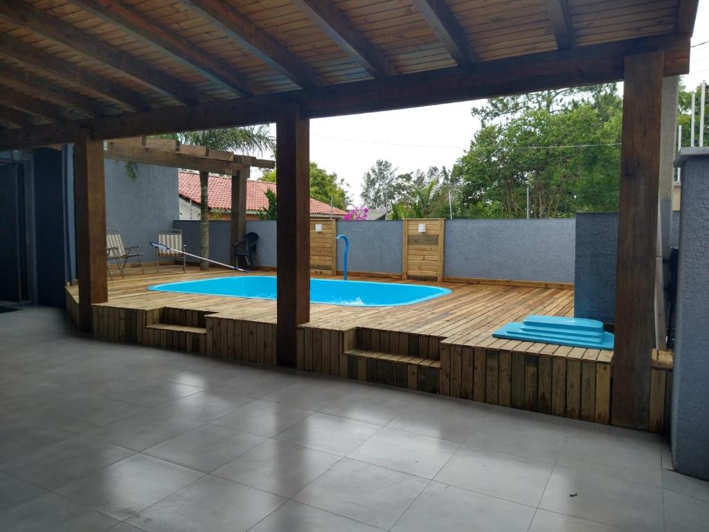 a patio with a swimming pool with a wooden deck at Casa confortável com piscina in Tramandaí