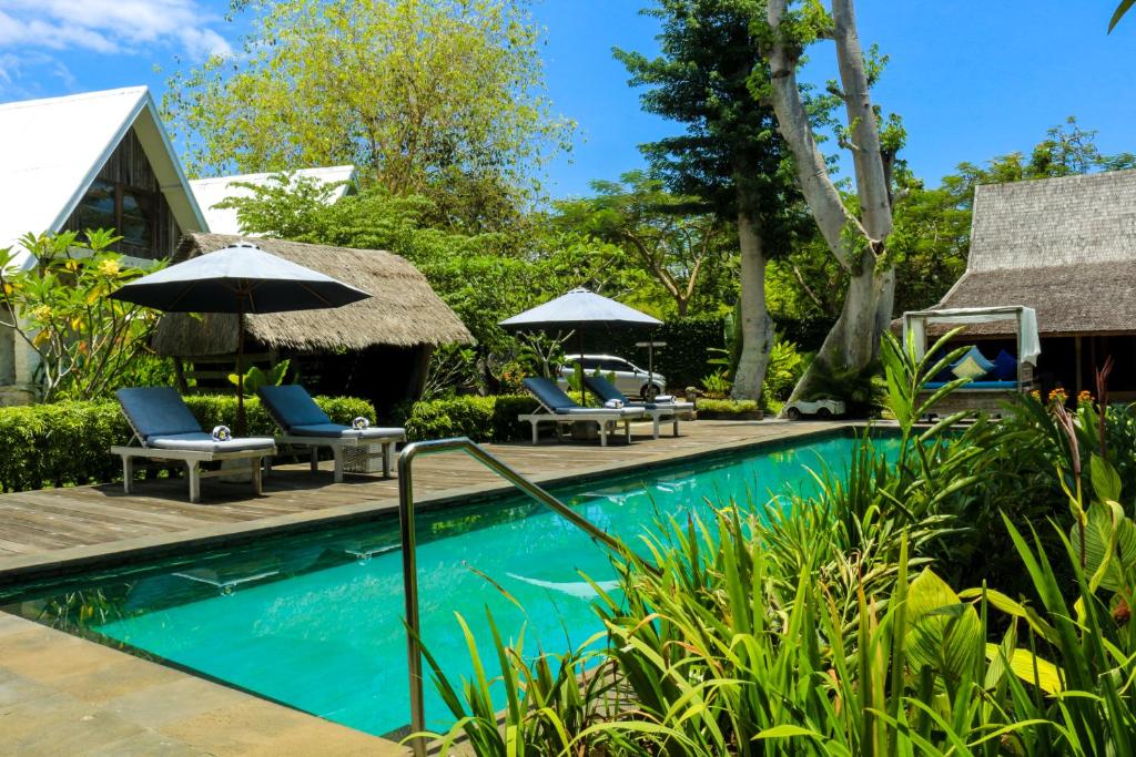 a pool at a resort with chairs and umbrellas at Chanteak Bali in Jimbaran