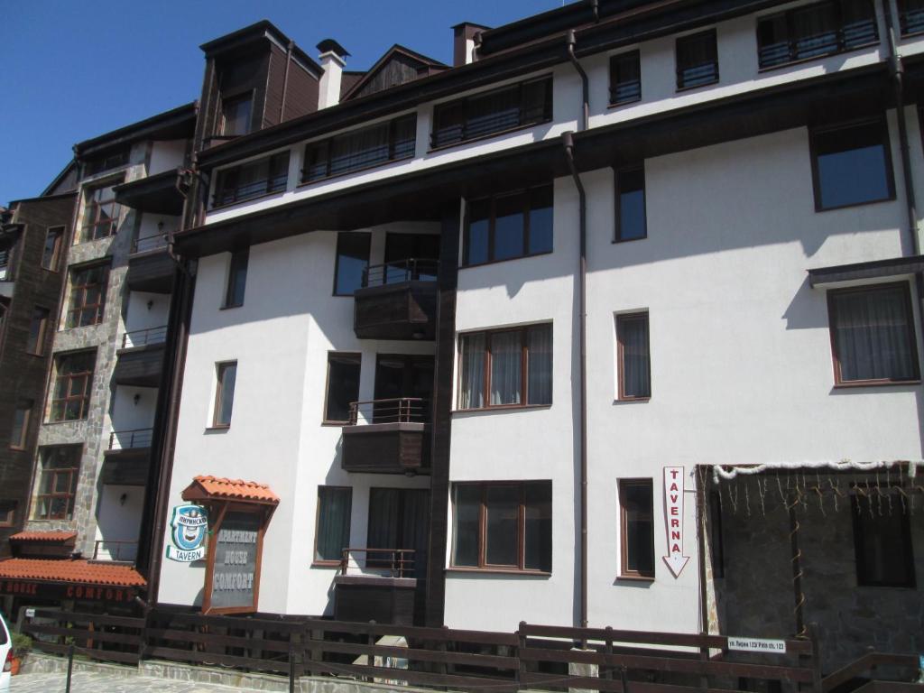 a white building with black windows at Comfort Private Apartments in Bansko