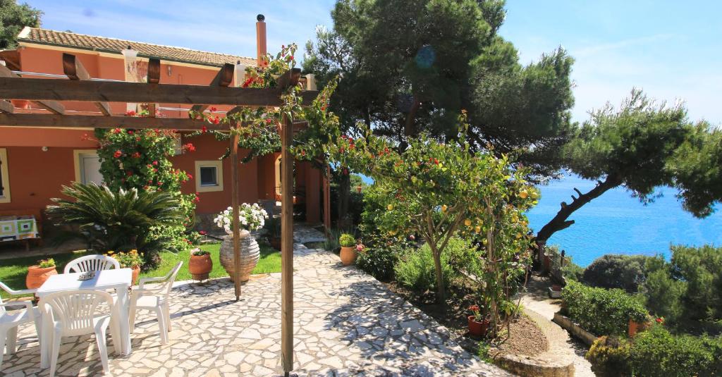 派萊卡斯的住宿－Villa Takis on Pelekas beach Apartment A with private garden and sea view，房屋前设有带桌椅的天井。