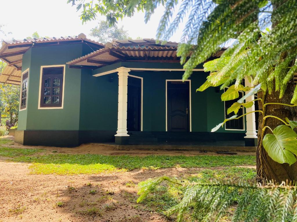 uma pequena casa verde com uma árvore em frente em Sigiri Siesta Homestay em Sigiriya