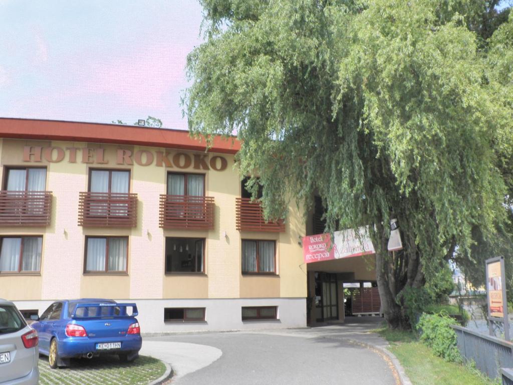 un hotel con un coche azul estacionado frente a él en Hotel Rokoko en Košice