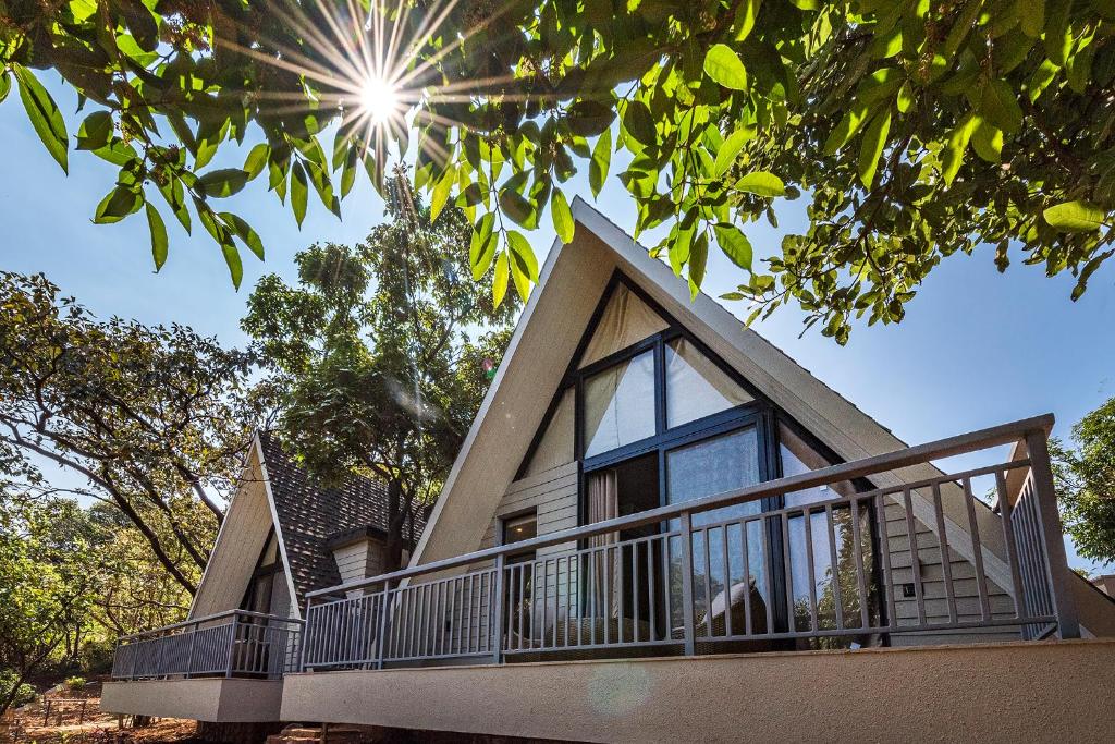 uma casa com uma varanda com o sol no céu em SaffronStays Hillside Harriers, Lonavala - A Frame chalets with bathtub for couples em Lonavala