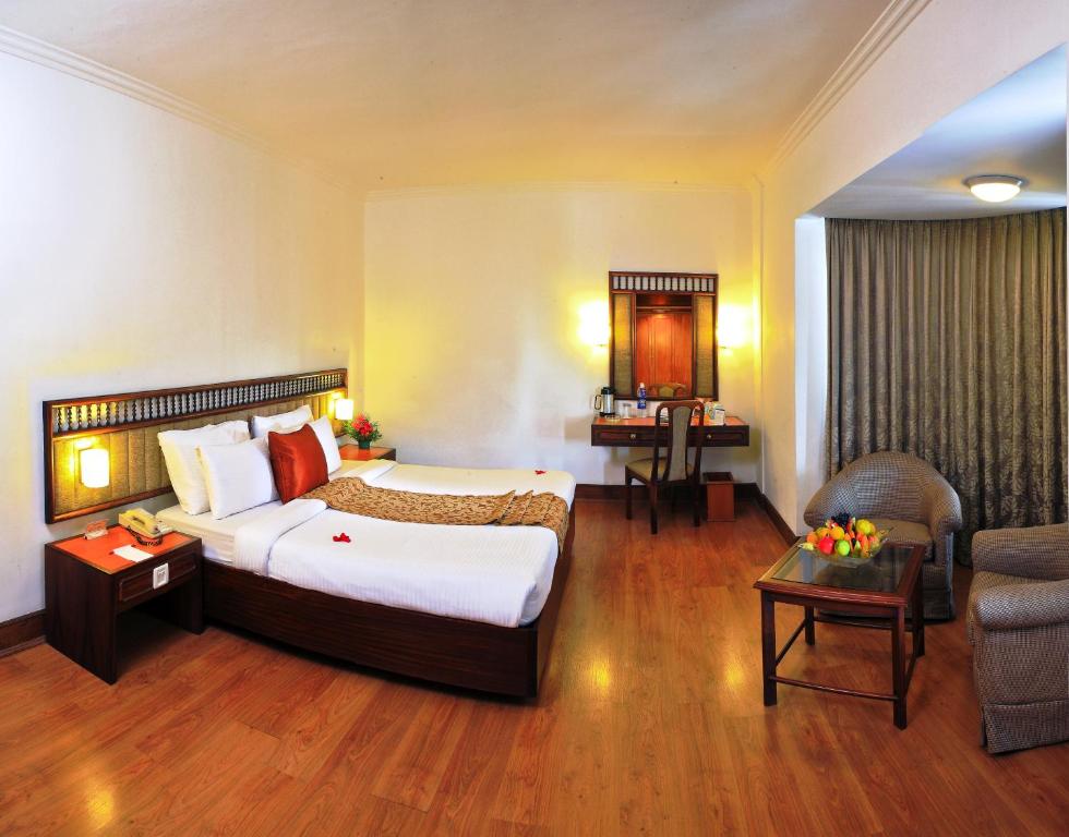 Habitación de hotel con cama grande y sofá en Hotel Abad Plaza, en Kochi