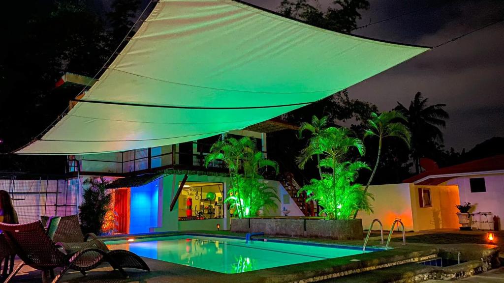 a house with a swimming pool with green lights at Parrot Resort Moalboal in Moalboal