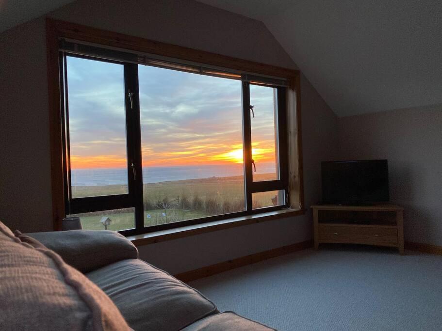 ein Wohnzimmer mit Sofa und großem Fenster in der Unterkunft Enegar Accommodation in Stromness