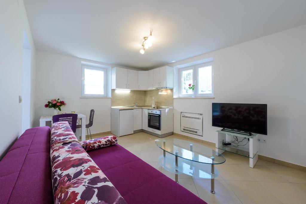 sala de estar con sofá púrpura y TV en Apartment Pavlina, en Dubrovnik
