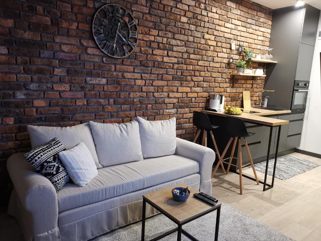salon z kanapą i ceglaną ścianą w obiekcie Klimatyczne mieszkanie w sercu Starego Podgórza w Krakowie