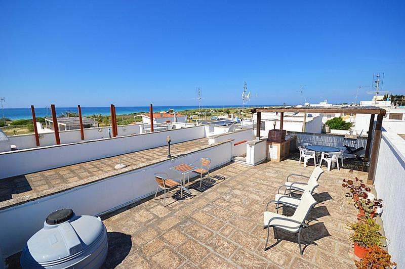 balkon ze stołem i krzesłami oraz oceanem w obiekcie Rif. 086 e 087 Maldive di SalentoINvacanza.Com w mieście Marina di Pescoluse