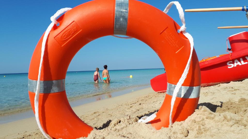 pomarańczowy pierścień ratujący życie na plaży z dwoma osobami w wodzie w obiekcie Rif. 086 e 087 Maldive di SalentoINvacanza.Com w mieście Marina di Pescoluse