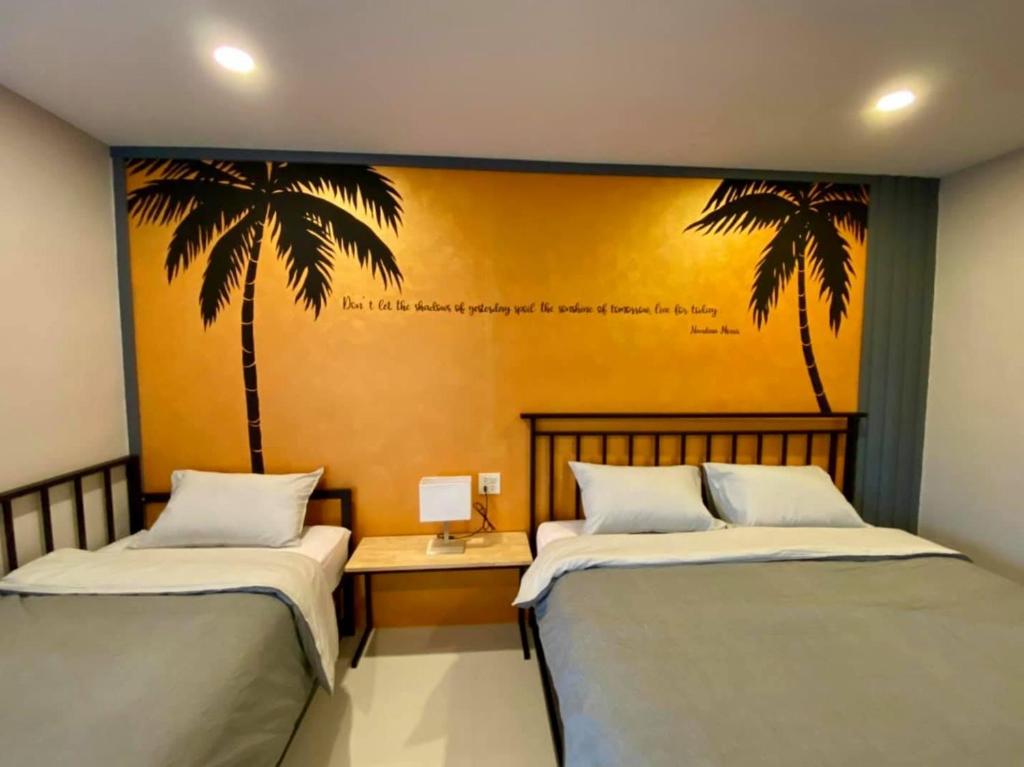 twee bedden in een kamer met palmbomen aan de muur bij บ้าน ชลรพี Baan Chonrapee in Ban Pak Nam Krasae