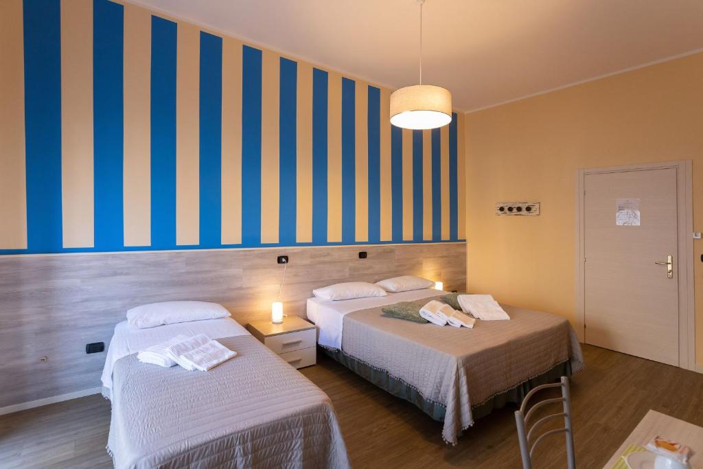um quarto de hotel com duas camas e uma parede listrada em L'OPERA ROOMS em Verona