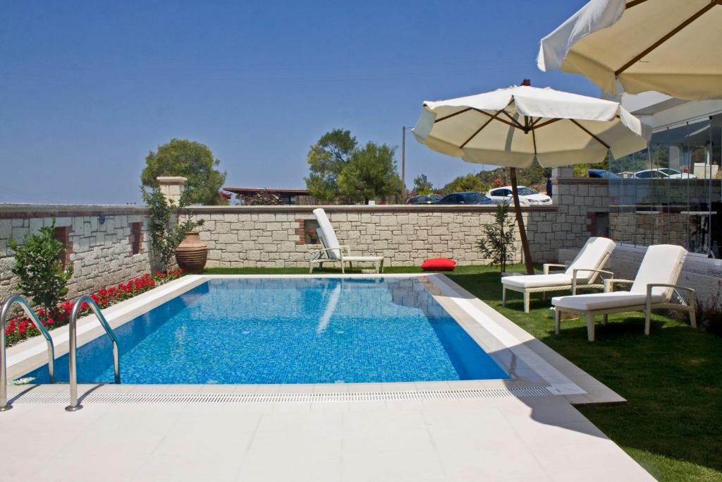 uma piscina com um guarda-sol e duas cadeiras e um guarda-sol em Lara Ilica Hotel em Cesme