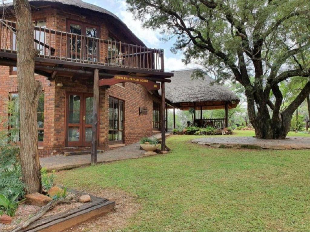 uma casa de tijolos com uma varanda e uma árvore em Hornbill Private Lodge Mabalingwe em Mabula